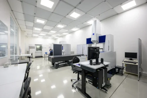 Ein heller, sauberer Messraum mit mehreren großen Koordinatenmessgeräten und einem Arbeitsplatz im Vordergrund.